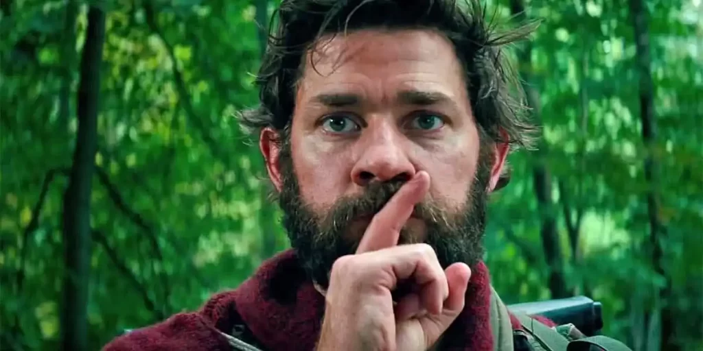 a quiet place- man in woods holding finger to his lips. coming to 31 nights of halloween on freeform. 